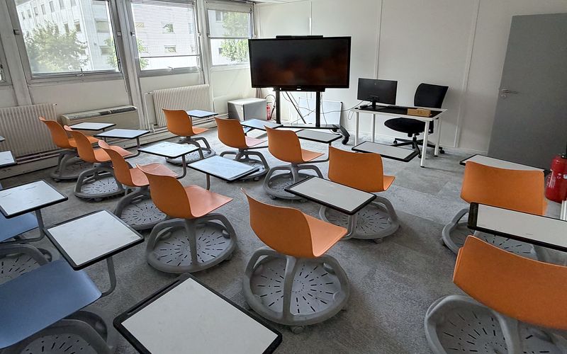 Salle de formation — sièges mobiles à tablette et écran interactif